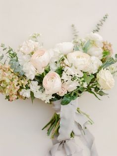 a bouquet of white and pink flowers with greenery on the top is tied to a gray ribbon