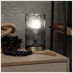 a glass vase sitting on top of a wooden table next to beads and a rope