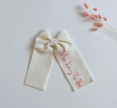 two white ties with pink writing on them next to some dried flowers and a plant