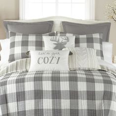 a bed with plaid sheets and pillows on top of it in front of a window