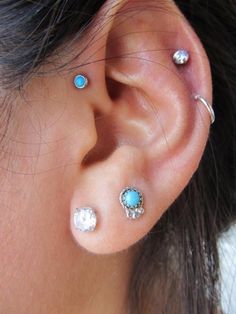 an ear with three different colored stones on it's side and two smaller ones in the middle