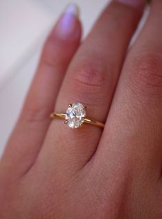 a close up of a person's hand with a diamond ring on their finger