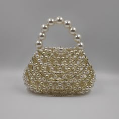 Introducing the stunning rhinestone pearl bag, meticulously handcrafted with love and passion by an Indian artisan using premium faux pearls. This show-stopping bag is destined to capture all eyes. More than just a stylish accessory, the micromini bag is a perfect gift for a myriad of occasions - birthdays, Valentine's Day, anniversaries, Mother's Day, engagements, festivals, and beyond. Unparalleled in versatility, the statement bag is tailored to various settings. Whether it's a nightclub part Gold Pearl Bags For Formal Occasions, Gold Pearl Evening Bag For Events, Gold Pearl Evening Bag, Formal Gold Pearl Bags, Gold Clutch With Pearl Embroidery, Gold Pearl Clutch With Pearl Embroidery, Glamorous Pearl Clutch With Pearl Handle, Party Embellished Pearl Evening Bag, Pearl Evening Bag With Pearl Handle For Events