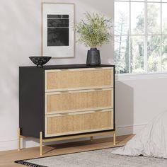 a black and beige dresser with drawers in a bedroom