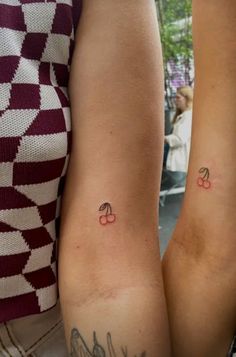 two people with matching tattoos on their legs, one is holding the other's arm