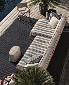 a couch and chair sitting on top of a wooden deck next to a body of water