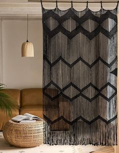 a living room with a brown couch and black macrame curtain on the wall