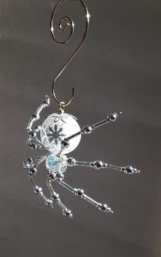 a metal spider hanging from a hook with beads and crystals on it's back