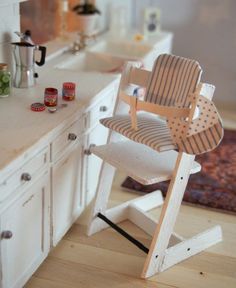 a toy chair sitting on top of a wooden stool next to a counter in a kitchen