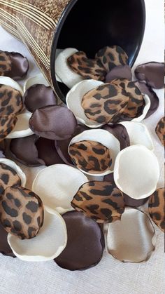 some brown and white flowers are on the ground next to a metal vase with an animal print pattern