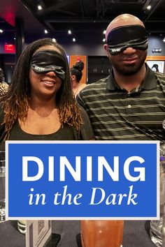 two people wearing blindfolds standing in front of a sign that says dining in the dark