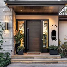 the front entrance to a modern home with potted plants