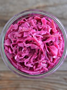 a glass jar filled with red cabbage on top of a wooden table