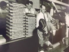 an old black and white photo of men working in a factory with stacks of money