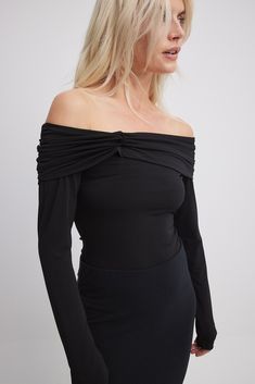 This long sleeve top features a form fit and a slightly sheer stretchy material. It has a folded off shoulder design with a twist detail and a rouched detail at the shoulders.