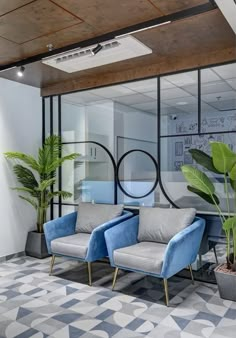 an office with two blue chairs and plants