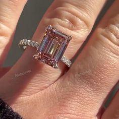 a woman's engagement ring with an emerald and diamonds