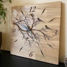 a wooden clock with birds and branches on it