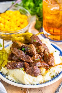 a plate full of meat and mashed potatoes with pickles next to the bowl