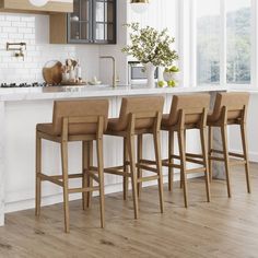 a kitchen with white walls and wooden flooring next to an island counter top, four stools in front of it