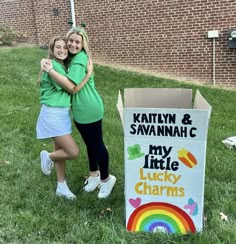 two young women hugging each other in front of a sign that says my lucky charms