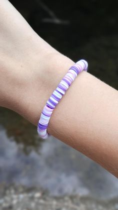 a woman's arm with a purple and white bracelet on it