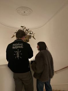 a man and woman standing next to each other in front of a chandelier