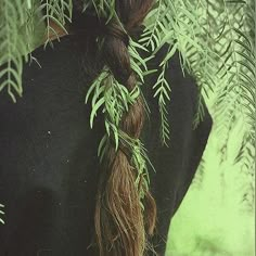 a woman with long red hair is standing in front of some green leaves and branches