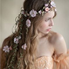 a woman with long hair and flowers in her hair is wearing a flowered headpiece