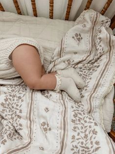 a baby is sleeping in a crib with white blankets and brown trimmings