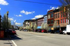 a city street lined with parked cars and tall buildings