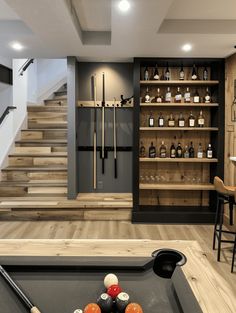 a pool table in front of some shelves with bottles on it