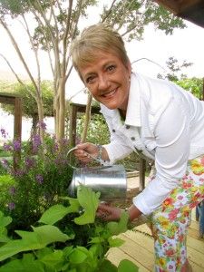 a woman is watering plants in the garden