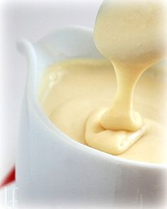 a spoon full of cream sitting in a white bowl