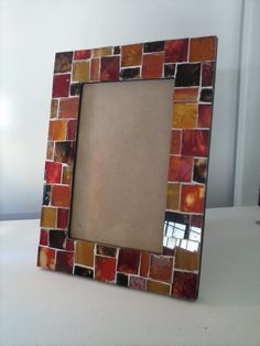 a small square frame made out of multicolored tiles on a white countertop