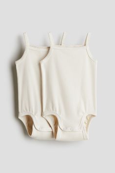 H&M Adorables. Sleeveless bodysuits in soft pima cotton jersey with delicate picot trim at shoulder straps and neckline. Narrow shoulder straps  square neckline  and snap fasteners at bottom for easy changing. Gathered seam around leg openings for added comfort and improved fit over diaper. Our cotton jersey has a high GSM for thicker  more durable quality without compromising on comfort. The H&M Adorables collection is a curated selection of high-comfort  quality pieces with a timeless appeal. Beige Bodysuit, Orange Bodysuit, Green Bodysuit, Blue Bodysuit, Cotton Plant, Grey Bodysuit, Pink Bodysuit