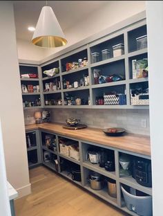 a kitchen with lots of shelves filled with food and containers on top of wooden flooring