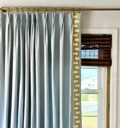 a window with blue curtains hanging from it's side and a curtain rod in front of the window