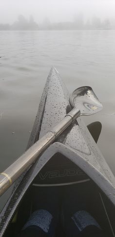 the front end of a kayak with its oar sticking out of the water