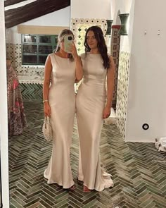 two women standing in front of a mirror taking a selfie