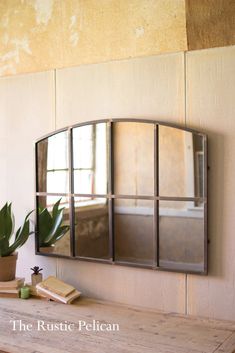 a mirror sitting on top of a wooden table next to a potted plant