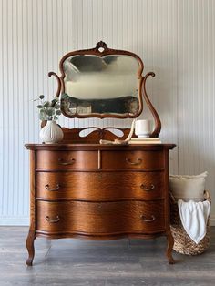 an old dresser with a mirror and vase on top