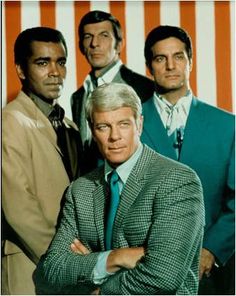 three men in suits and ties are posing for a photo with an american flag behind them