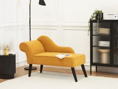 a yellow chair sitting on top of a white rug next to a black book shelf