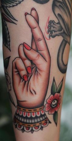 a woman's arm with tattoos on it and a hand holding the peace sign