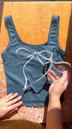 a woman is holding onto an old tank top that has been stitched into it