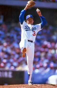 a baseball player throwing a ball on top of a field in front of a crowd