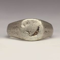 This handmade signet ring has a little 1.2mm Champagne diamond bead set for a subtle sparkle. The face is 10x10mm with a tapering shank for comfort.  Made by casting recycled sterling silver in beach sand, it has a lovely chunky feel. The sand mould creates the texture you can see on the ring. The ring pictured is a size M. Your ring will be made to order and each one comes out differently.  The rustic and irregular nature of our sandcast range comes from Justin's own technique; as the name suggests each ring is cast in beach sand. With a different mould used each time, every ring is totally unique - make it that little bit more special by sending us your own beach sand.   You can buy the mould the ring is cast in if you like. If you would like to use some of your own metal or sand please Diamond Signet Ring, Mens Jewellery, Silver Signet Ring, Thumb Ring, Bead Set, Signet Rings, Ring Pictures, Ring Minimalist, Thumb Rings