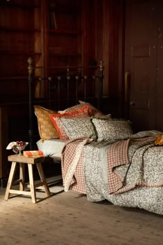 a bed sitting in a bedroom next to a night stand with pillows on top of it