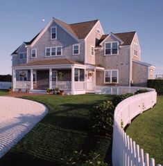 a large house sitting on top of a lush green field next to a white picket fence